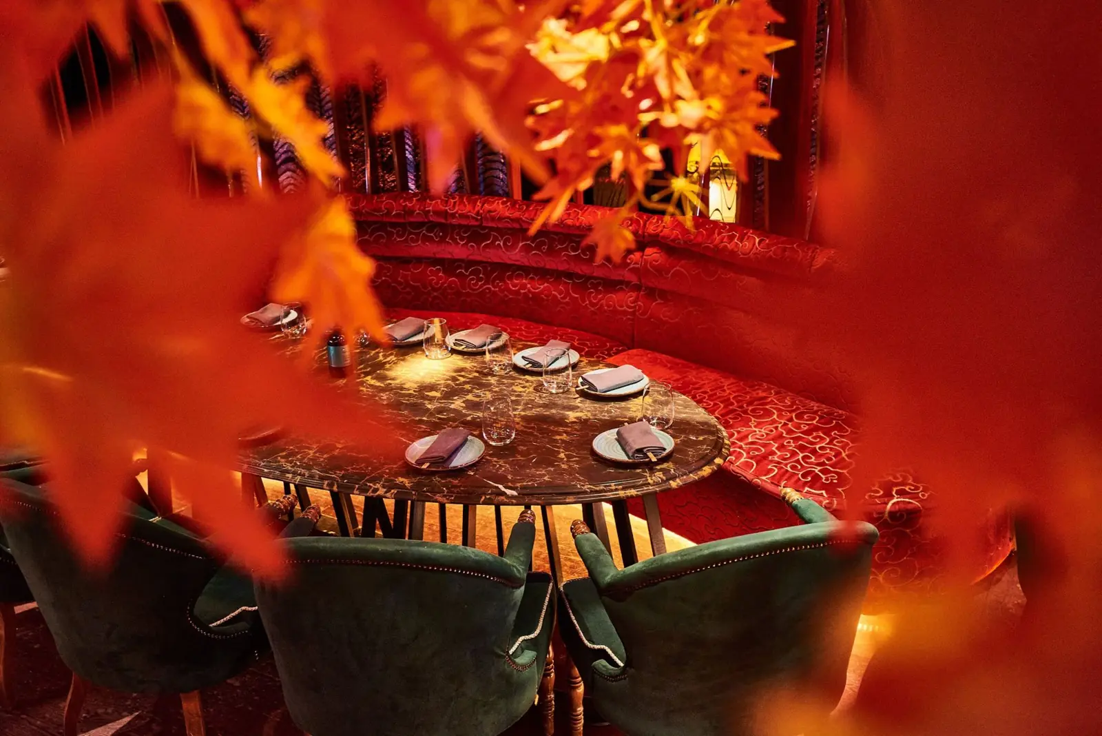 Red velvet banquette seen through maple leaves