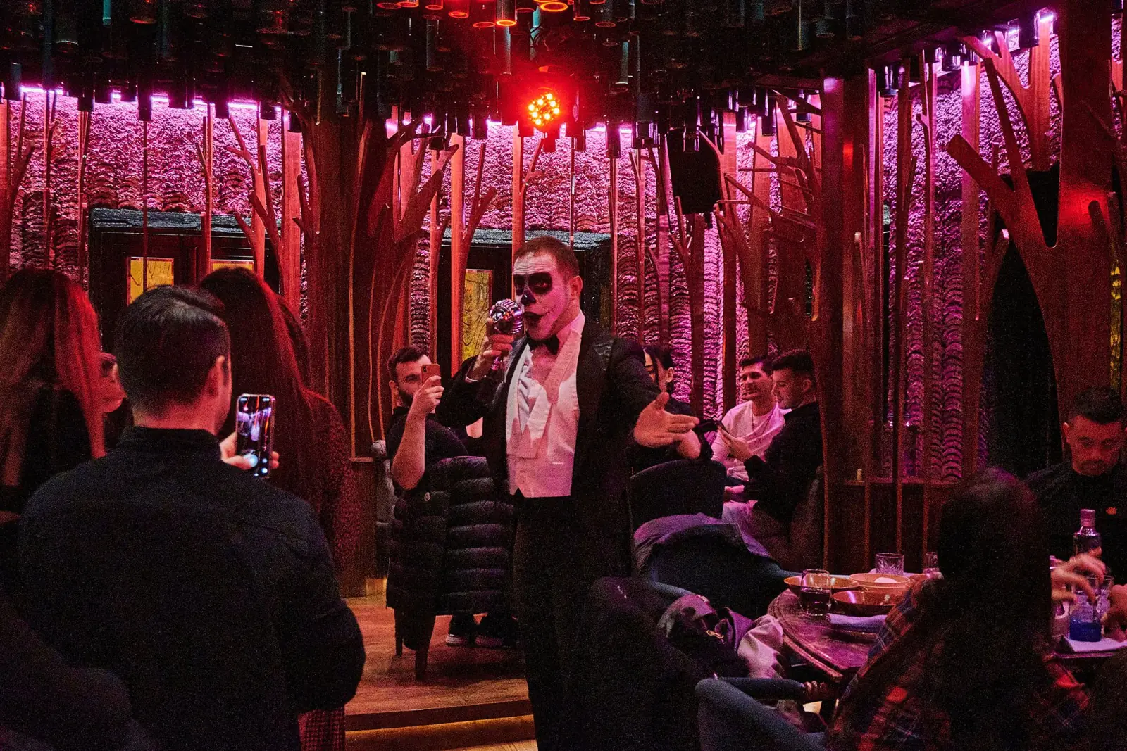 Performer singing among the guests under pink light